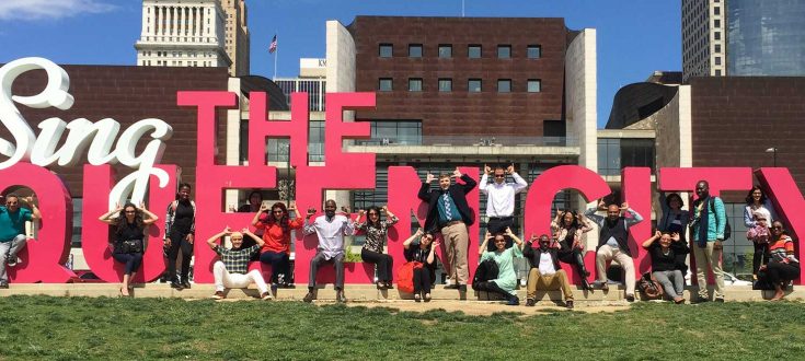 Group of people in front of Sing Queen City Sign